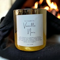 a candle with the words vanilla noir sitting next to a fire