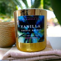 vanilla tropic breeze candle on a table next to a plant